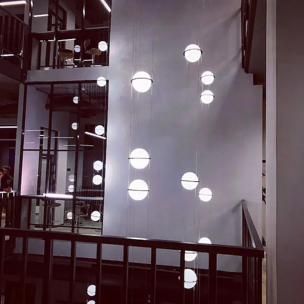 большая дизайнерская люстра из подвесных светящихся шаров в вечернем интерьере офисного здания