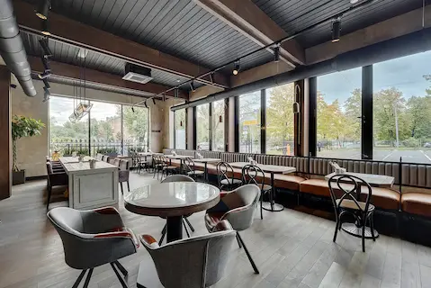 интерьер просторного ресторана с черными трековыми светильниками