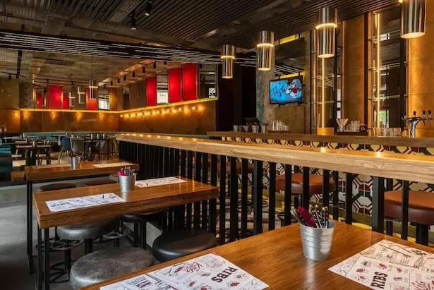 красивый светлый интерьере дизайнерского ресторана Frank с полированными люстрами из нержавейки над баром