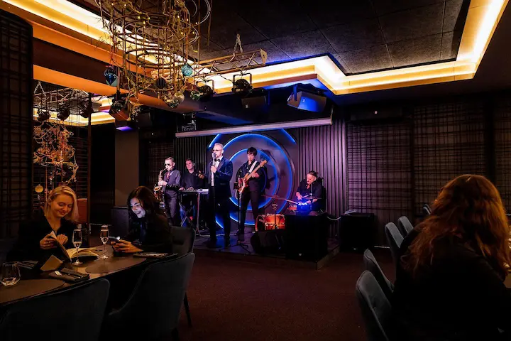 дизайнерская латунная люстра на фоне джаз группы выступающей не сцене