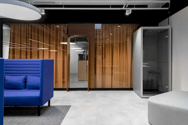 интерьер офиса с синим диваном и белыми светодиодными светильниками отражающимися в стекле