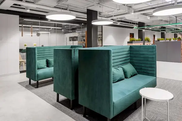 круглые подвесные светильники на фоне зеленых диванов в офисе