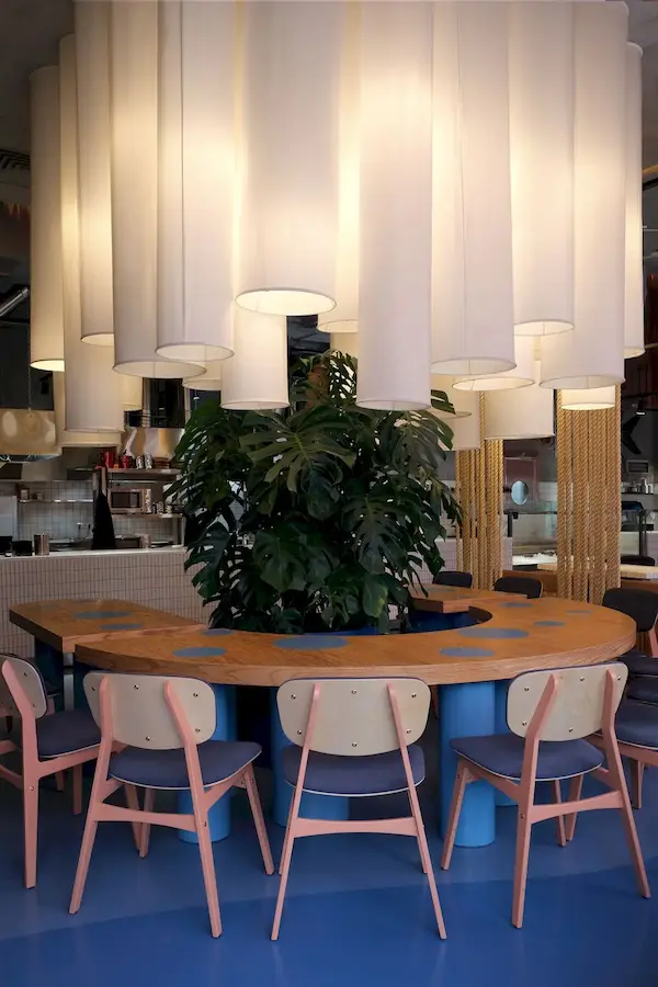 много белых светильников в виде длинных абажуров плотно свисающих с потолка крупным планом над столом в ресторане