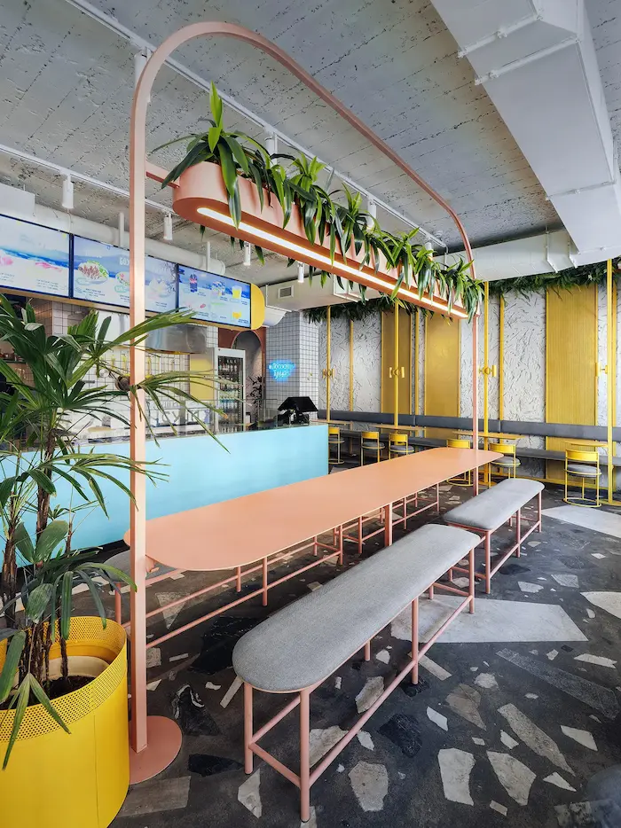 длинный светодиодный светильник в виде кашпо с цветами над столом в ресторане Pobo