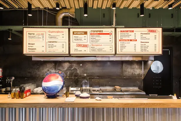 интерьер бара в стиле лофт с большим светлым лайтбоксом с меню в Забегаловке